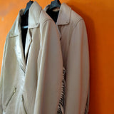 two leather jackets with white fringes hanging orange back ground